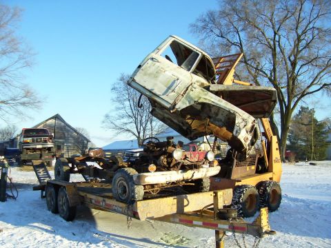1979 Ford Pickup - A truck cab is being removed from its chassis, which is loaded onto a trailer in a snowy yard.