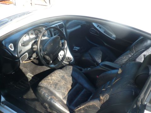 1996 Ford Mustang - The interior of a car shows worn black leather seats and a dashboard with gauges.