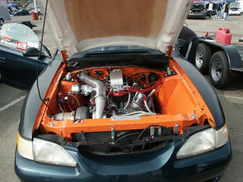 1996 Ford Bronco - Customized engine bay a turbocharger and vibrant orange accents. A second vehicle is partially visible.