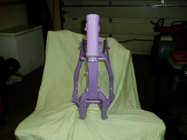Purple motorcycle frame on a light green cloth in a garage