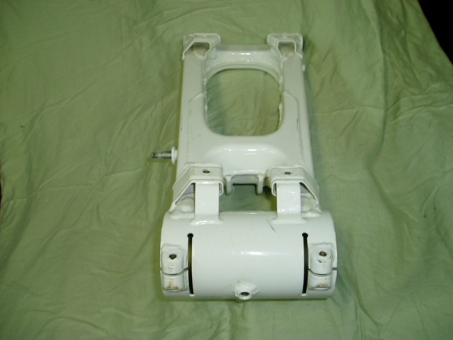 White suspension component with visible bolts and slots, on a green cloth background
