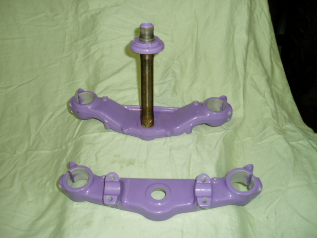Two purple motorcycle triple clamps, one with a metal shaft sticking up