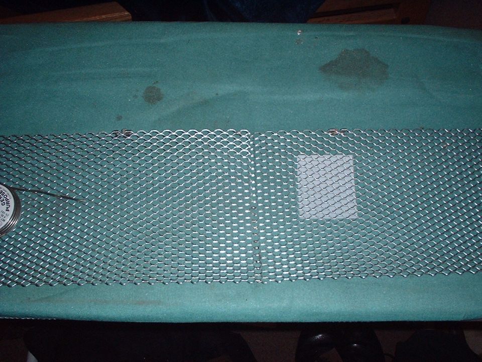 Metal mesh grille with a small circular gauge on the left