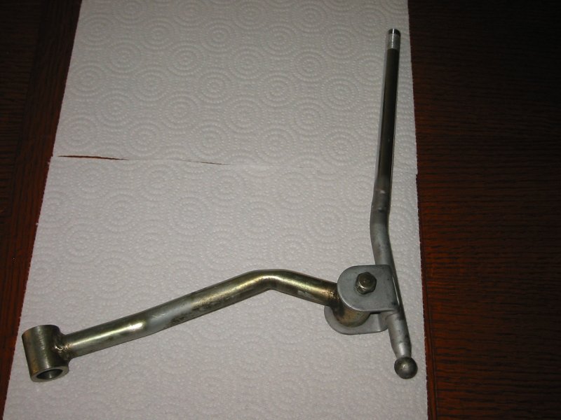 Bare metal shifter linkage arm and pivot bracket on a paper towel
