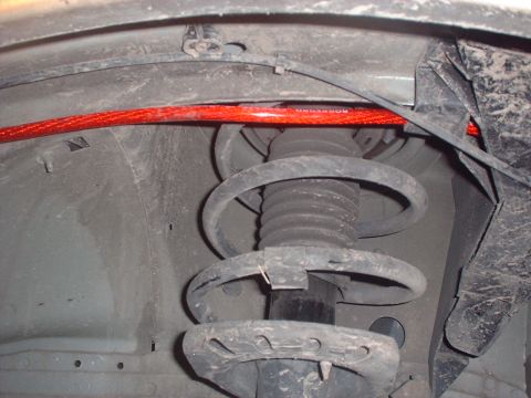 2000 Ford Taurus - Close-up view of a red sway bar and suspension strut, likely from the underside of a vehicle.