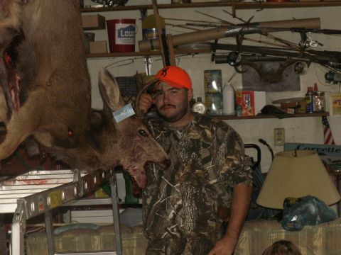 1995 Ford Bronco - Hunter poses with a harvested deer in a garage or workshop setting, surrounded by equipment.
