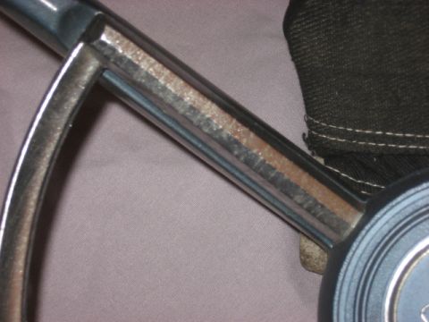 1972 Ford F-100 - A close-up view of a steering wheel's chrome spoke, showing wear and a portion of a black fabric cover.