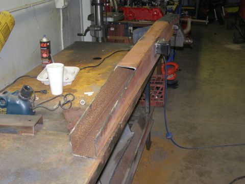 1993 Ford Bronco - A workbench holds various tools and a large metal beam with a sanding belt attached.