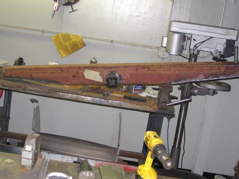 1993 Ford Bronco - A metal beam is being worked on in a workshop, clamped to a workbench.