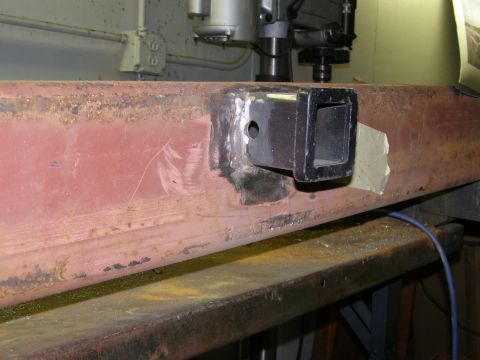 1993 Ford Bronco - A close-up of a rusty metal beam with a trailer hitch receiver welded onto it, indicating repair or modification.