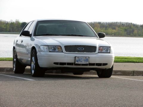2003 Ford Crown Victoria - White 2003 Ford Crown Victoria parked near a lake on a cloudy day.