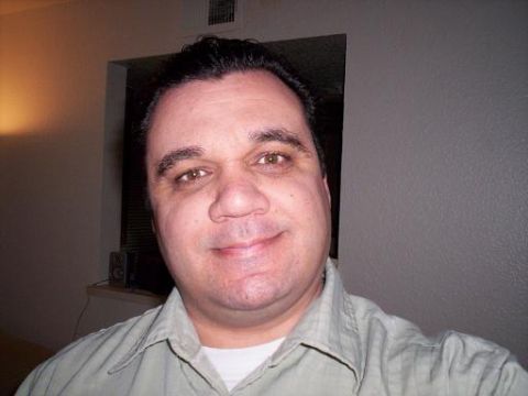 1989 Ford Bronco - A man smiles for a selfie in a room with a light on the left and a window behind him.