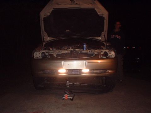 2000 Ford Taurus - Front view of a 2000 Ford Taurus with the hood open, illuminated by its headlights.