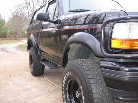 1967 Ford Mustang - A black Ford Bronco is parked on a concrete surface next to a gravel road.