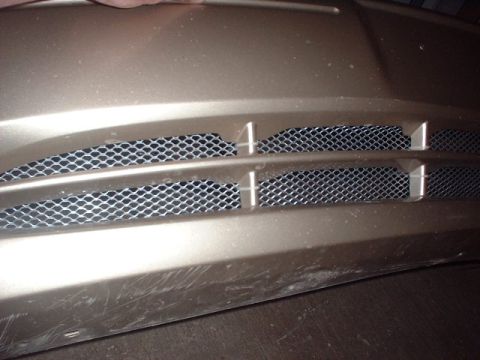 2000 Ford Taurus - The front grille of a car features a mesh pattern within horizontal slats.