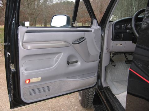 1967 Ford Mustang - The interior of a black truck is visible with the driver's door open, revealing the dashboard, steering wheel, and door panel.