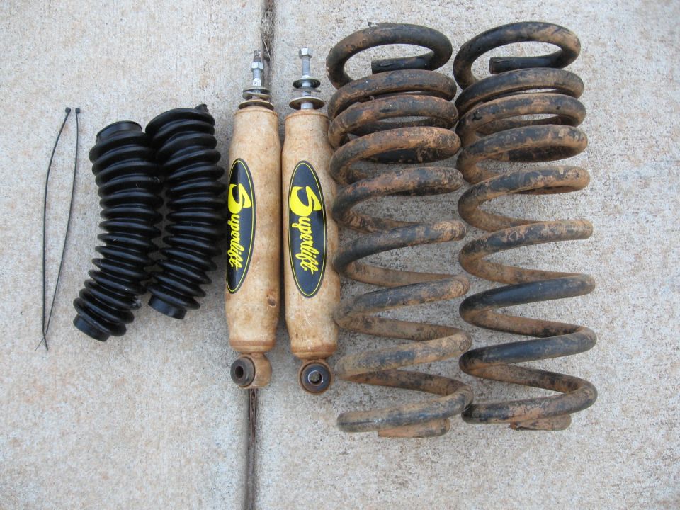 Used Superlift shocks, shock boots and dirty coil springs laid out on concrete