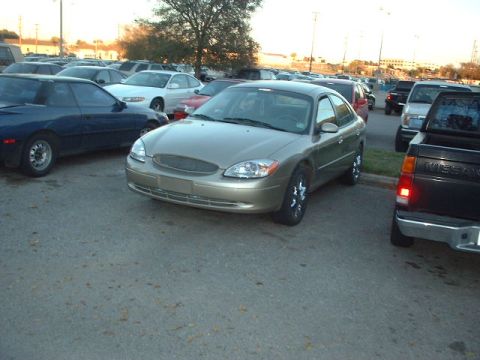 2000 Ford Taurus - A gold 2000 Ford Taurus sedan is parked in a lot, viewed from the front three-quarter angle.