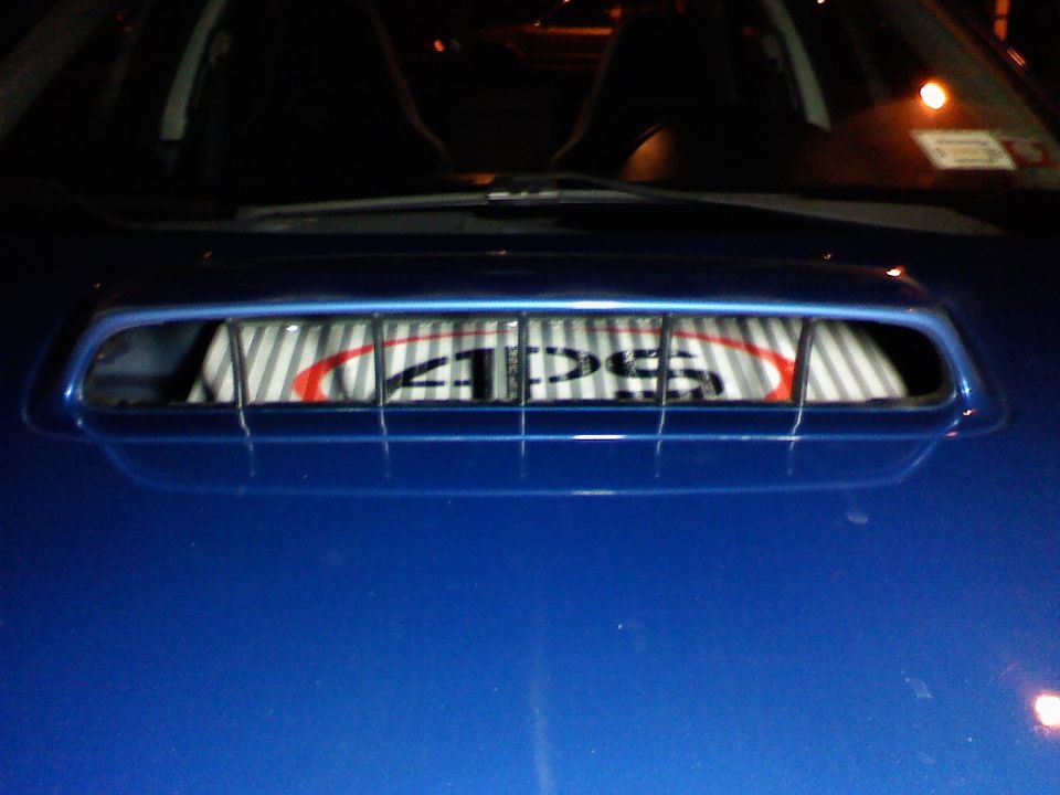 Blue car hood scoop with a license plate visible inside. The plate has 'APS' on it