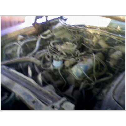 1972 Ford Ranchero - A cluttered engine bay with many hoses and wires visible, obscuring specific vehicle details.