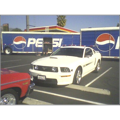 1972 Ford Ranchero - A white Ford Mustang is parked in a lot with two Pepsi trailers behind it.