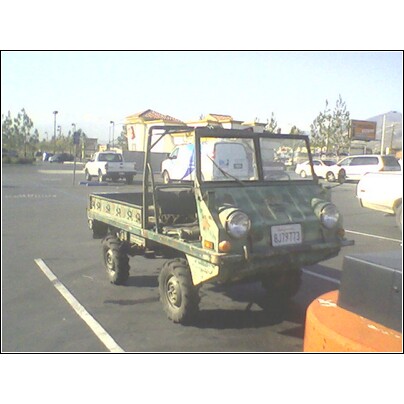 1972 Ford Ranchero - A green utility vehicle with a flatbed is parked in a lot, showing its front and side profile.
