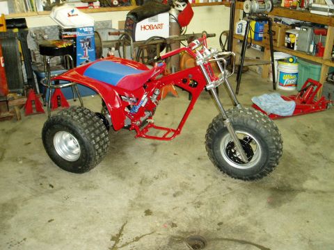 2000 Ford E350 - This red three-wheeled ATV frame, a blue seat and large tires, is shown in a workshop setting.
