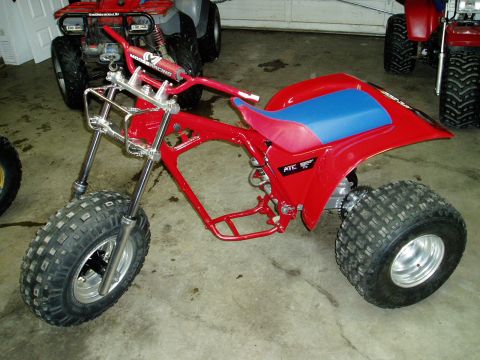 2000 Ford E350 - A red three-wheeler is parked in a garage with other ATVs visible in the background.