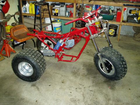 2000 Ford E350 - A red three-wheeled ATV frame is shown in a workshop, with tools and shelves in the background.