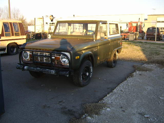 Green early Ford Bronco parked on a gravel lot