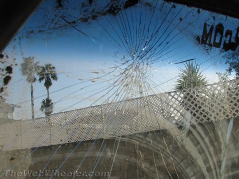 1987 Suzuki Samurai - View through a heavily damaged windshield shows palm trees and a white fence.