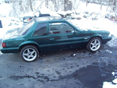 1991 Ford Mustang - Green 1991 Ford Mustang coupe parked on a snowy driveway with winter trees in the background.