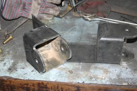 1991 Ford Bronco - Fabricated metal brackets sit on a workbench, ready for installation or further work.