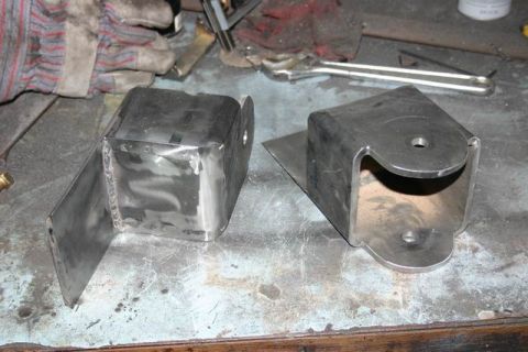 1991 Ford Bronco - These custom metal brackets appear to be fabricated parts, possibly for automotive modification, resting on a work surface.
