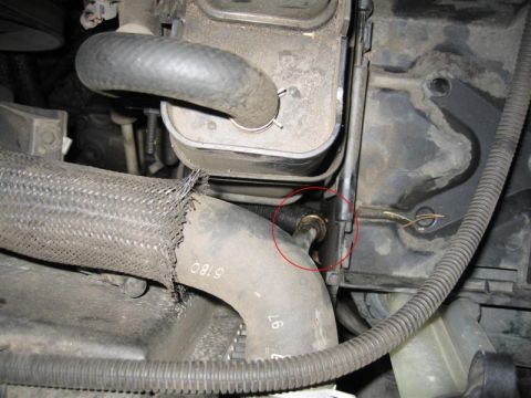 1994 Ford Probe - This image shows a close-up view of a damaged engine hose and its connection point, likely for maintenance or repair.