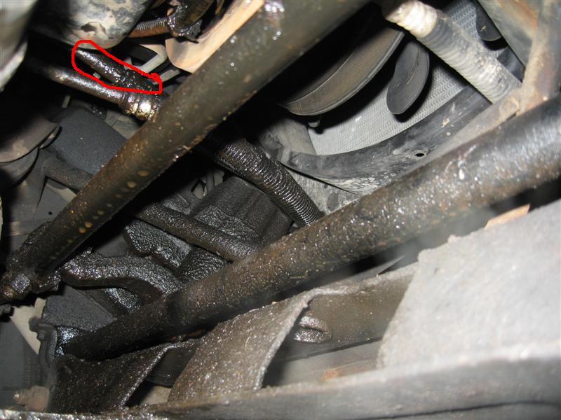 Greasy engine bay hoses and metal parts, with a red circle around a leaky connection