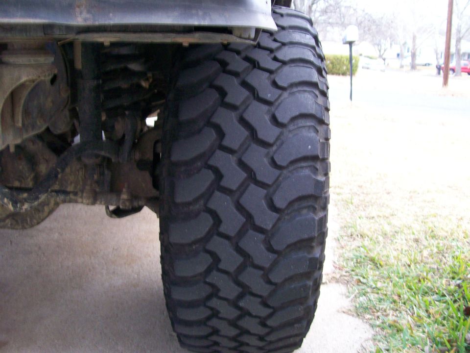 Close-up of aggressive mud-terrain tire on a lifted truck in a driveway