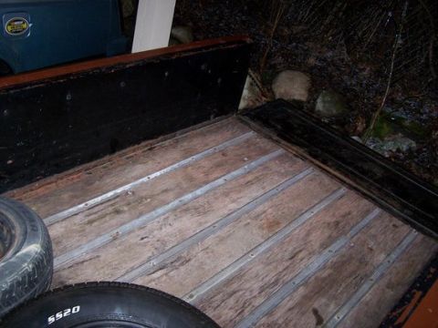 1979 Chevrolet C/K Pickup - The interior of a truck bed shows weathered wooden planks and metal strips, with two spare tires present.