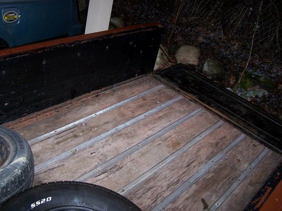 Truck bed with wooden planks and metal strips, two tires visible. One tire has "5520" written on it