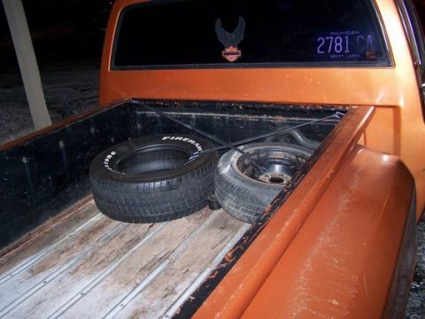1979 Chevrolet C/K Pickup - The rear bed of an orange 1979 Chevrolet C/K Pickup contains two tires and a Michigan license plate.