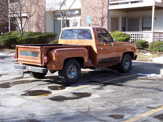 Rear 3/4 view of a brown 1977 Chevrolet C/K pickup truck parked in a lot
