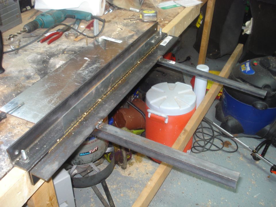 Steel angle iron with fresh welds on a workshop bench