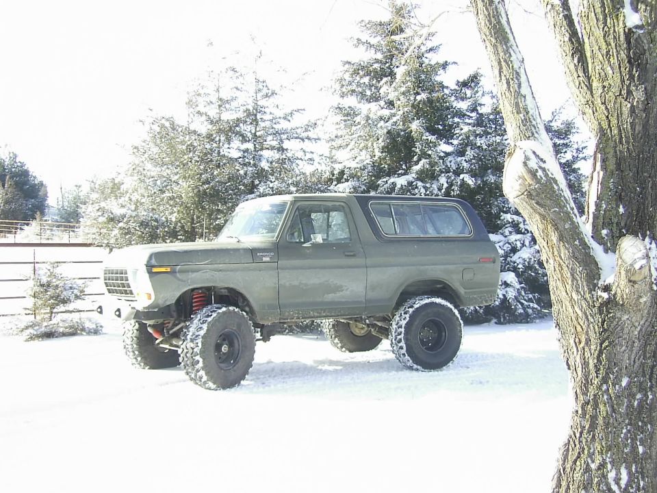 Lifted green 1978 Ford Bronco parked in a snowy landscape with trees