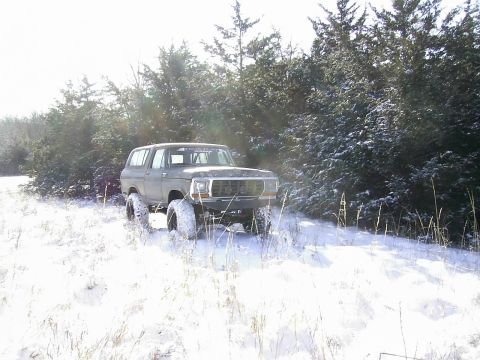 1978 Ford Bronco - A green 1978 Ford Bronco navigates a snowy landscape with large off-road tires.