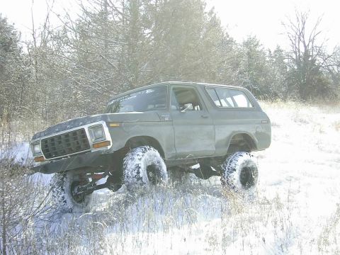 1978 Ford Bronco - A 1978 Ford Bronco navigates a snowy, wooded terrain.