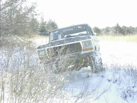 1978 Ford Bronco - A 1978 Ford Bronco navigates a snowy, off-road landscape with a "FOUR PLAY" sticker visible on its windshield.