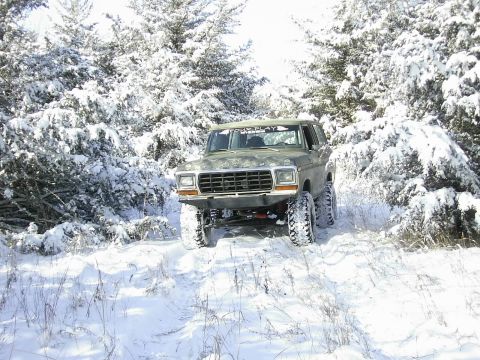 1978 Ford Bronco - 1978 Ford Bronco navigating a snow-covered path through a wooded area.