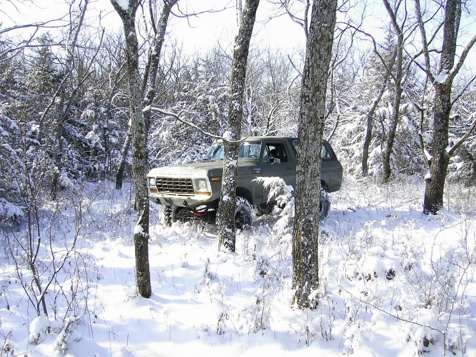 1978 Ford Bronco in snow, front 3/4 view, light colored grille, dark body, off-road tires