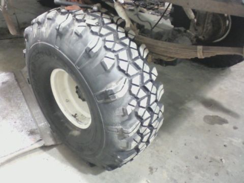 1992 Ford F-350 - A close-up view of a large off-road tire and the vehicle's suspension system, showing the leaf springs.