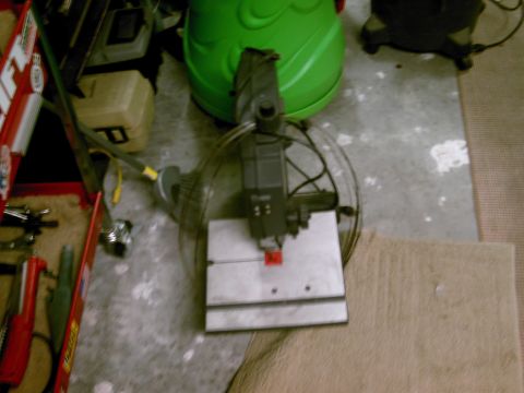 1986 Ford Bronco - A band saw sits on a concrete floor next to a green object and a toolbox.